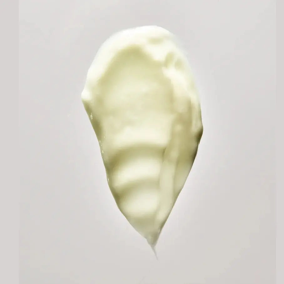 A dollop of Young Goose Premium Skincare Cream, a creamy off-white lotion infused with natural ingredients, is spread on a smooth light gray surface, ideal for attaining a youthful complexion.