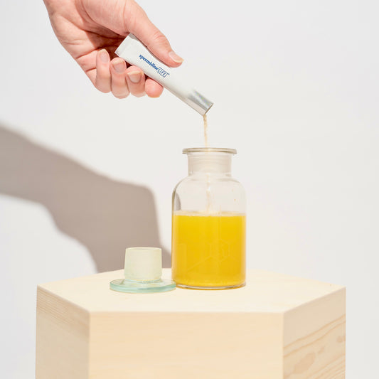 A person pouring spermidineLIFE® Pro+ 4800mg 10 Pack orange juice into a jar.